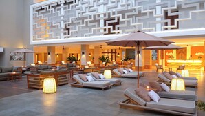A spacious lobby with multiple seating areas, including sofas and lounge chairs, and a reception desk. - The Bandha Hotel & Suites (Legian)