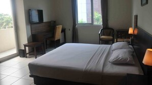 A hotel room with a bed, a desk with a chair, a television, and a window with curtains. - Losari Blok M  Hotel Jakarta (Jakarta)