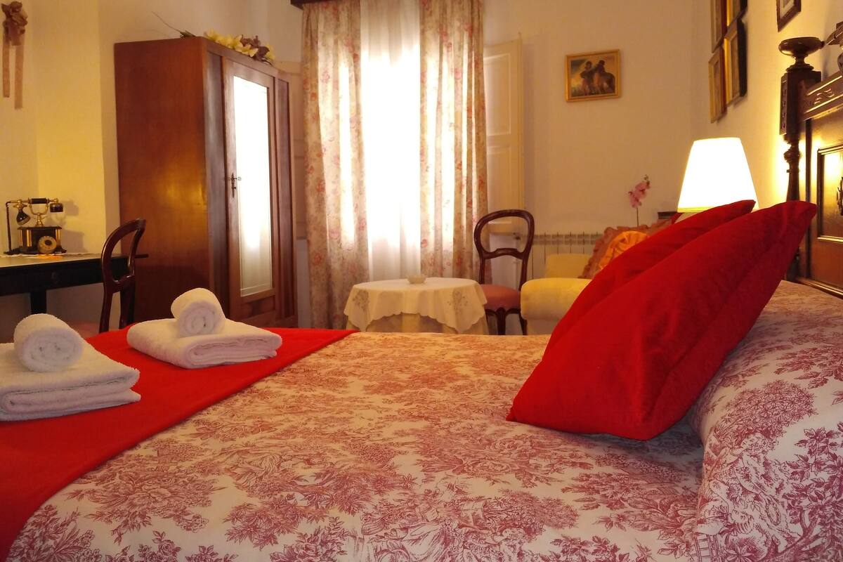 Quarto de hotel com cama, escrivaninha, cadeira, mesa e armário.