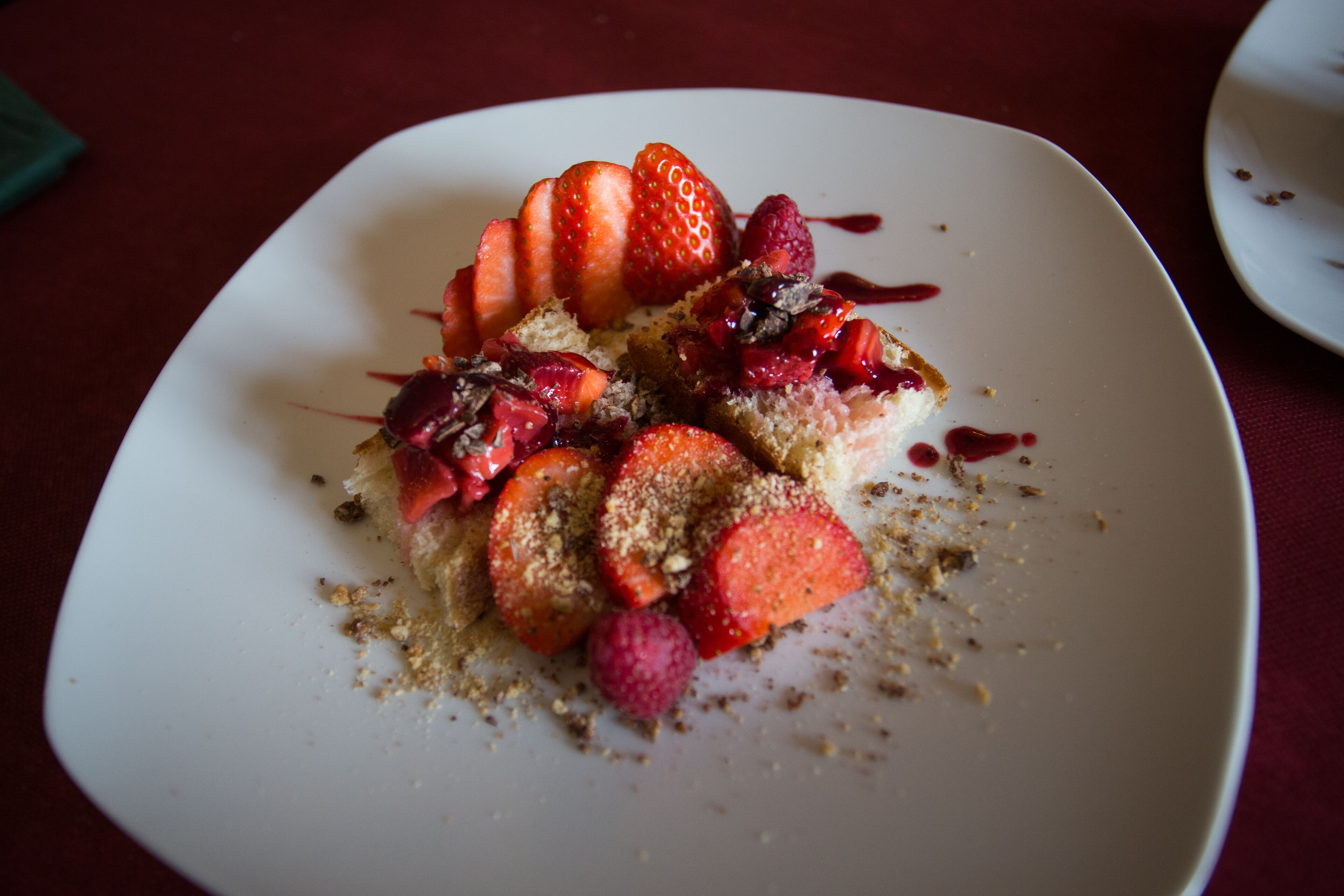 A dessert plate with strawberries, raspberries, and a berry sauce on a white plate.