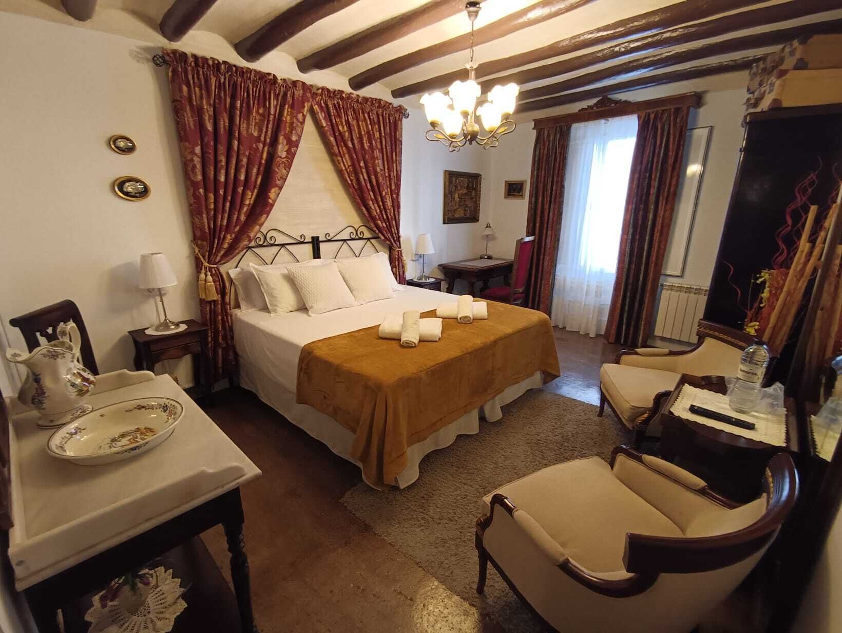 A hotel room with a bed, a desk, a chair, and a chandelier.