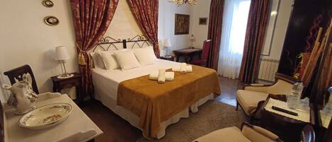 A hotel room with a bed, a desk, a chair, and a chandelier.