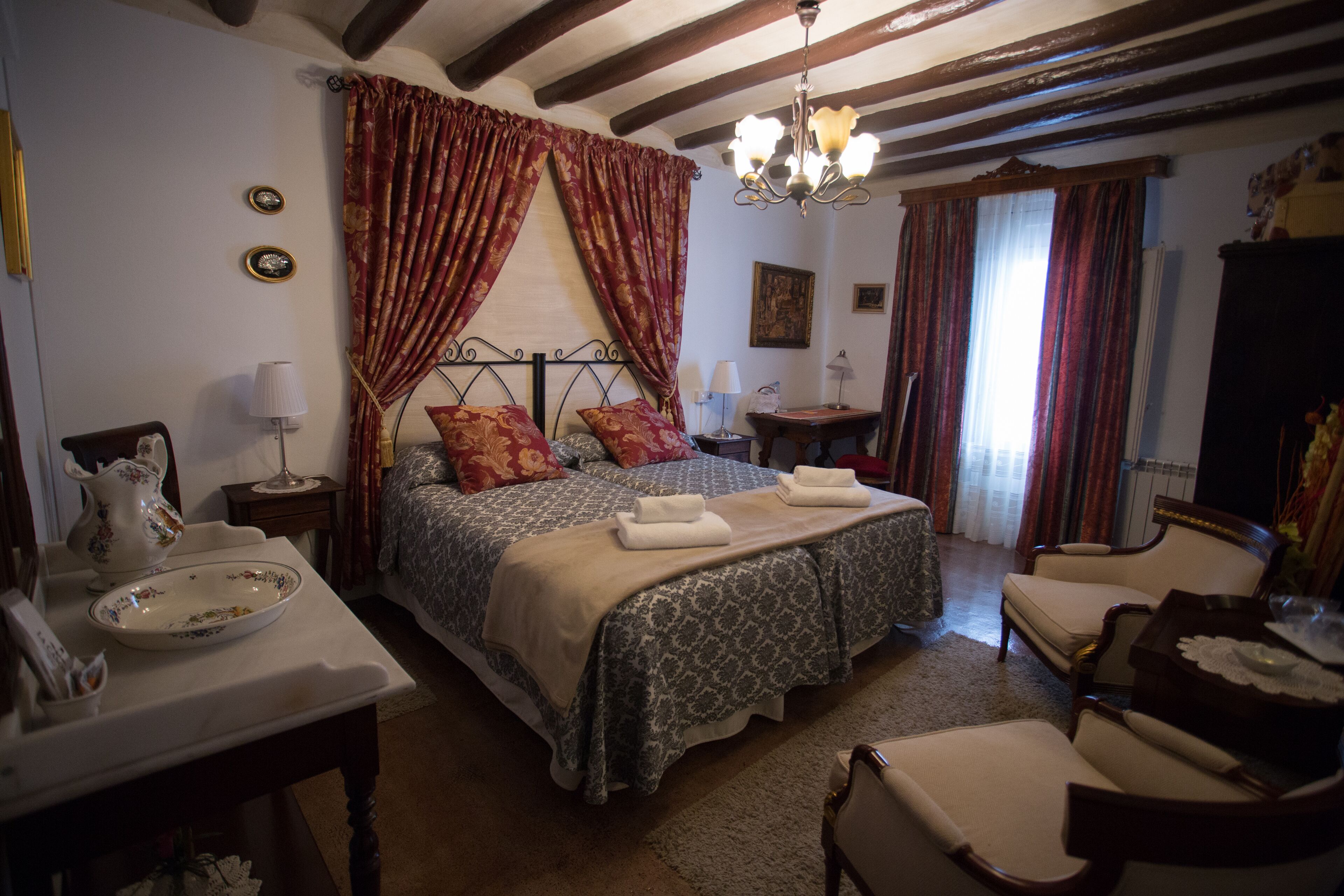 Un dormitorio tradicional con cama, mesitas de noche, una silla y un candelabro.