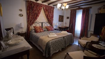 Un dormitorio tradicional con cama, mesitas de noche, una silla y un candelabro.