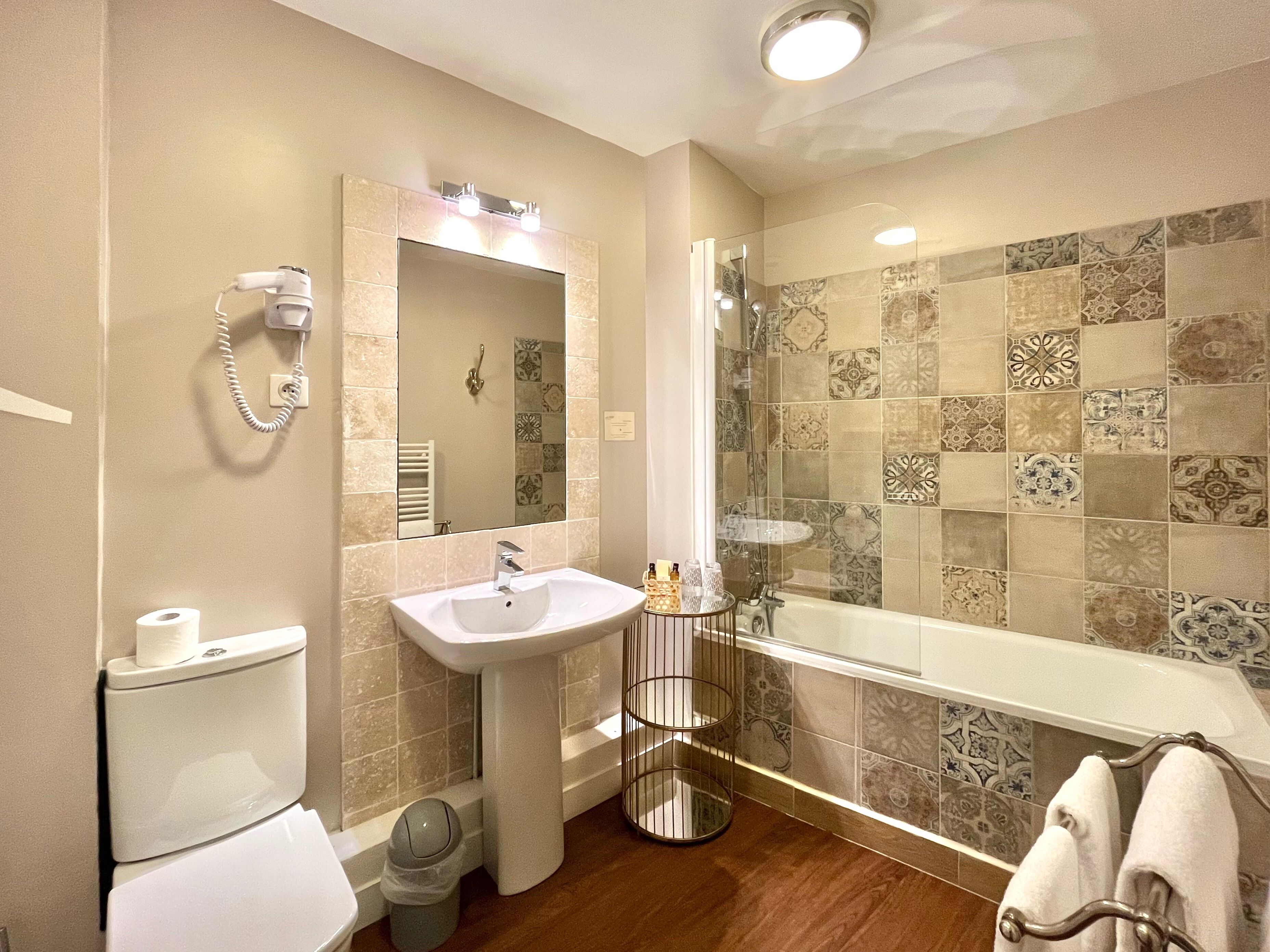 A bathroom with a sink, mirror, toilet, and shower.