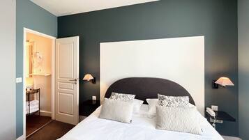 Une chambre à coucher avec un grand lit, deux lampes de chevet, une table de chevet et une porte donnant sur une salle de bain.