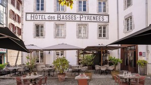 A hotel with outdoor seating, potted plants, and a sign reading 'HOTEL des BASSES PYRENEES'. - Hôtel des Basses Pyrénées (Bayonne)