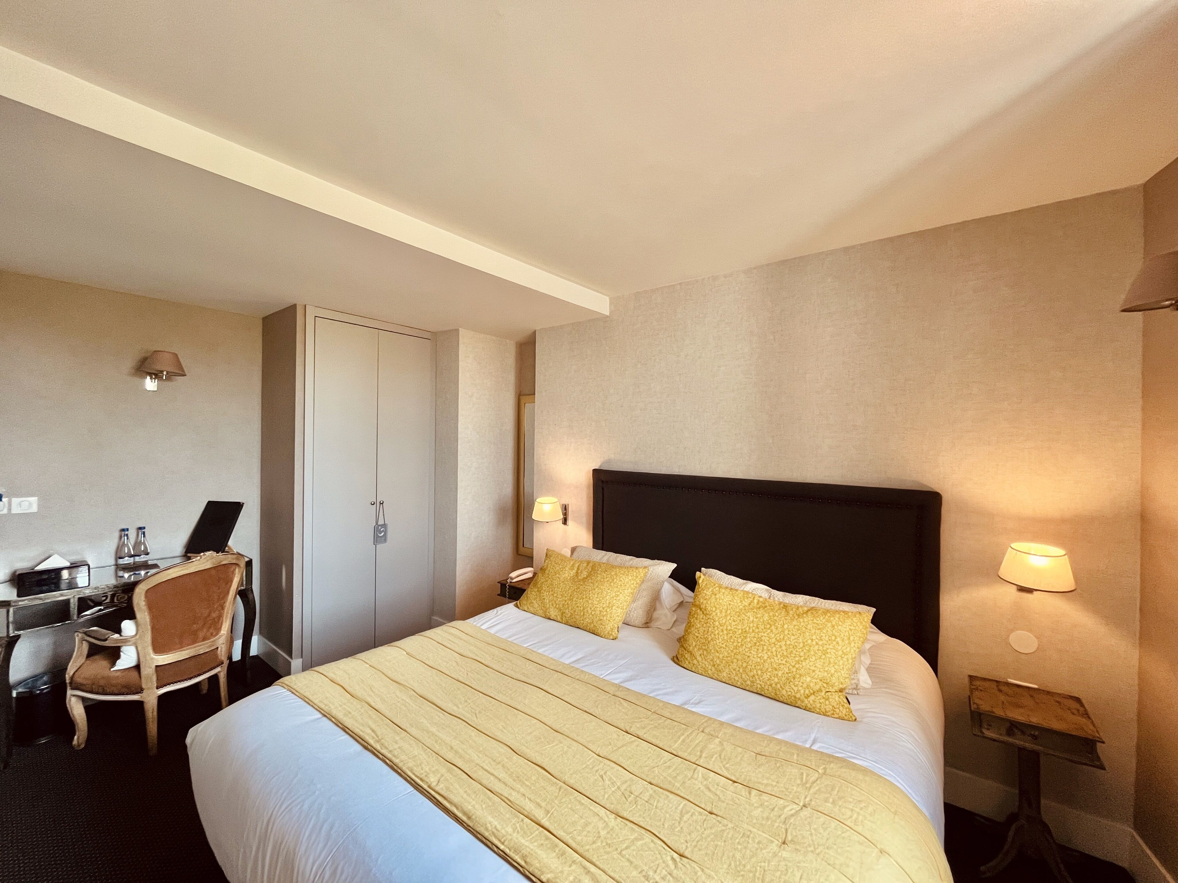 Ein Hotelzimmer mit einem großen Bett, einem Schreibtisch mit Stuhl, einem Kleiderschrank und zwei Nachttischlampen.