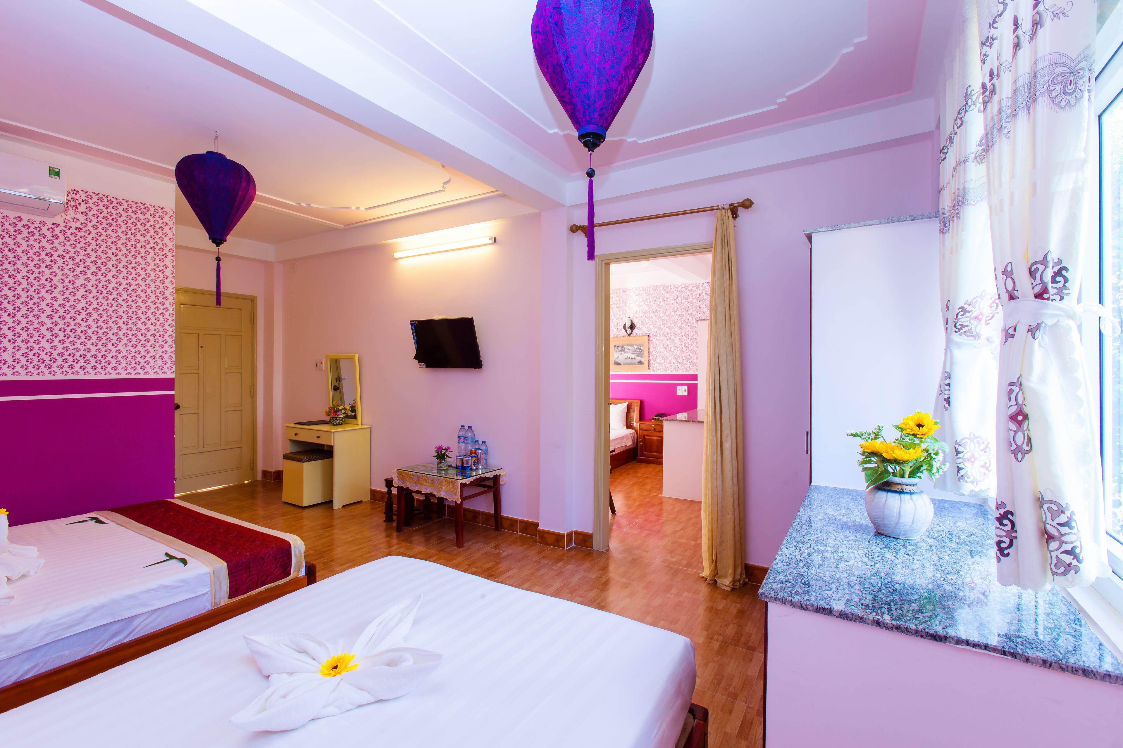 A hotel room with a bed, a desk, a chair, a TV, and a bathroom visible through an open door.