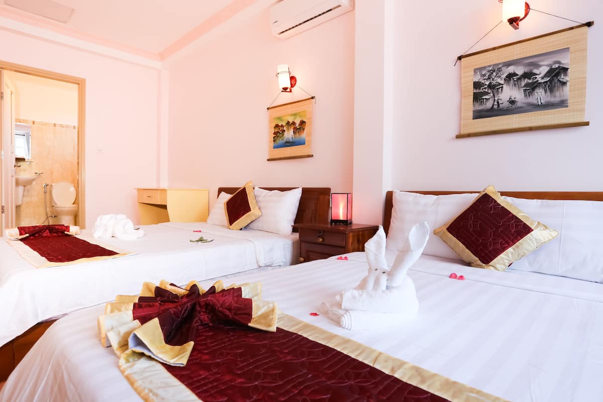 Une chambre d’hôtel avec deux lits, une table de chevet, une commode, une lampe fixée au mur et un tableau.