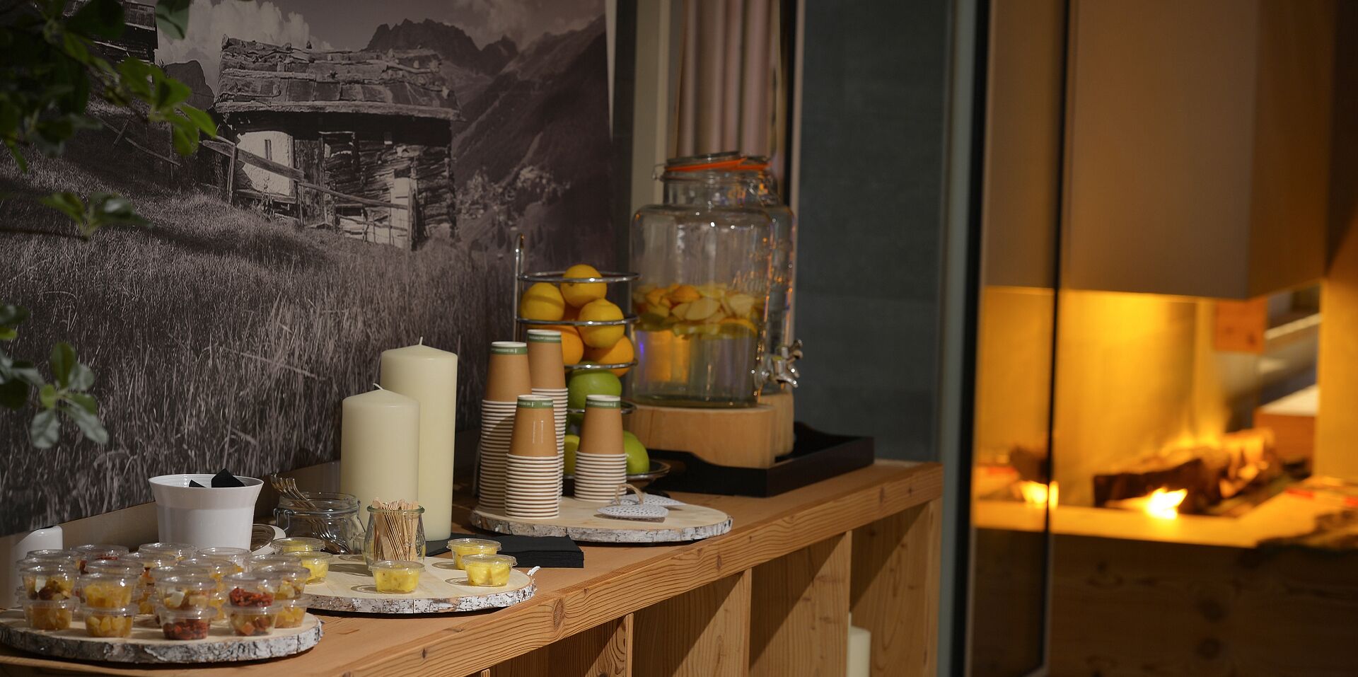 A buffet setup with various food items, including fruits and desserts, arranged on a wooden table.