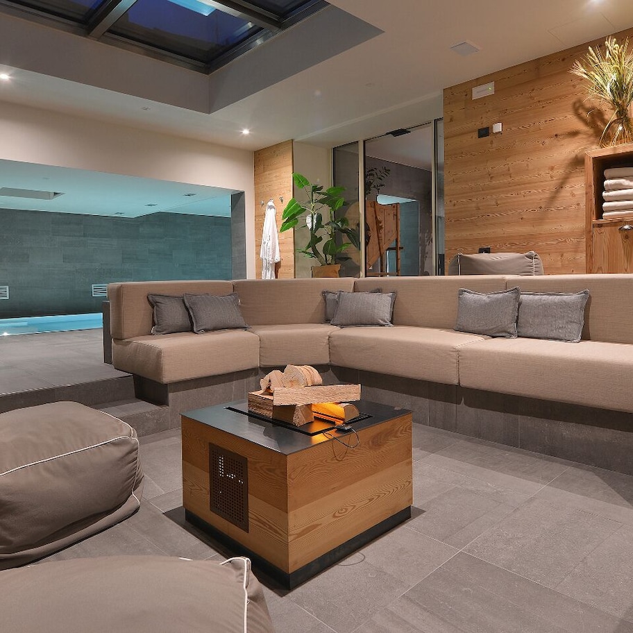 A modern living room with a large L-shaped sofa, a small wooden coffee table, and a stone wall.