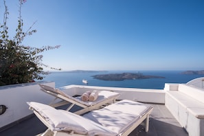 A terrace with sun loungers and a view of the sea. - Karpimo Horizon - Caldera View with private hot tub (Santorini)