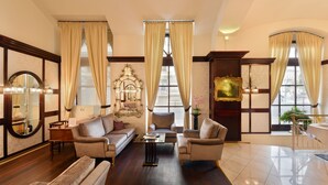 A spacious living room with a sofa, armchairs, a coffee table, and a fireplace. - Hotel Am Schubertring (Vienna)