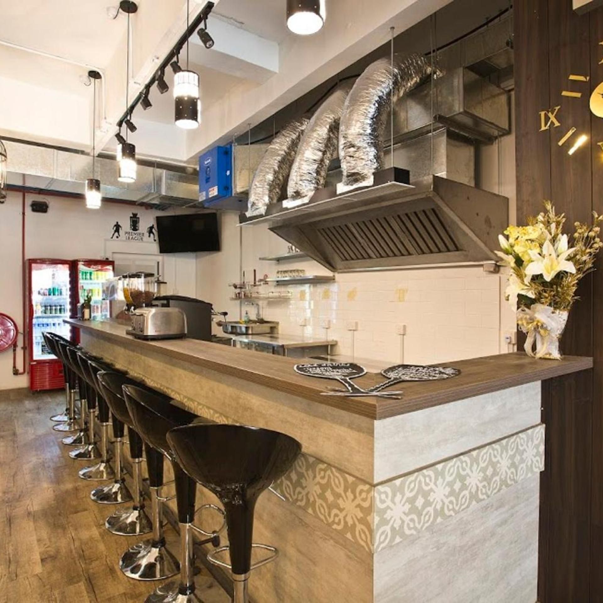 A bar area with stools, a counter, and a television screen.