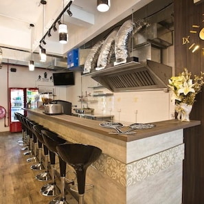 A bar area with stools, a counter, and a television screen. - 7 Wonders Hostel (Singapore)