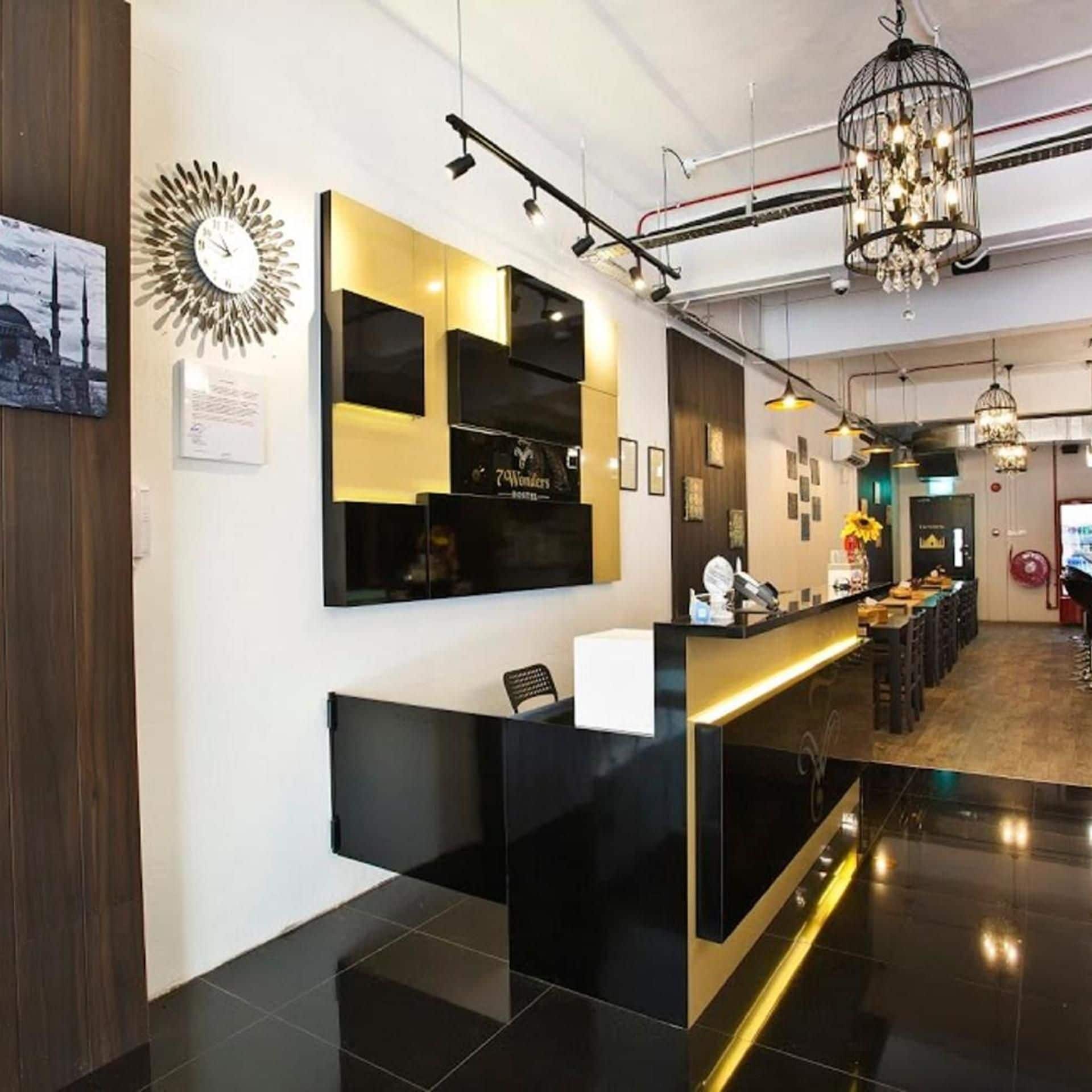 A reception area with a black and gold reception desk, a wall-mounted clock, and a chandelier.