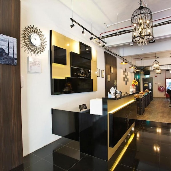A reception area with a black and gold reception desk, a wall-mounted clock, and a chandelier.