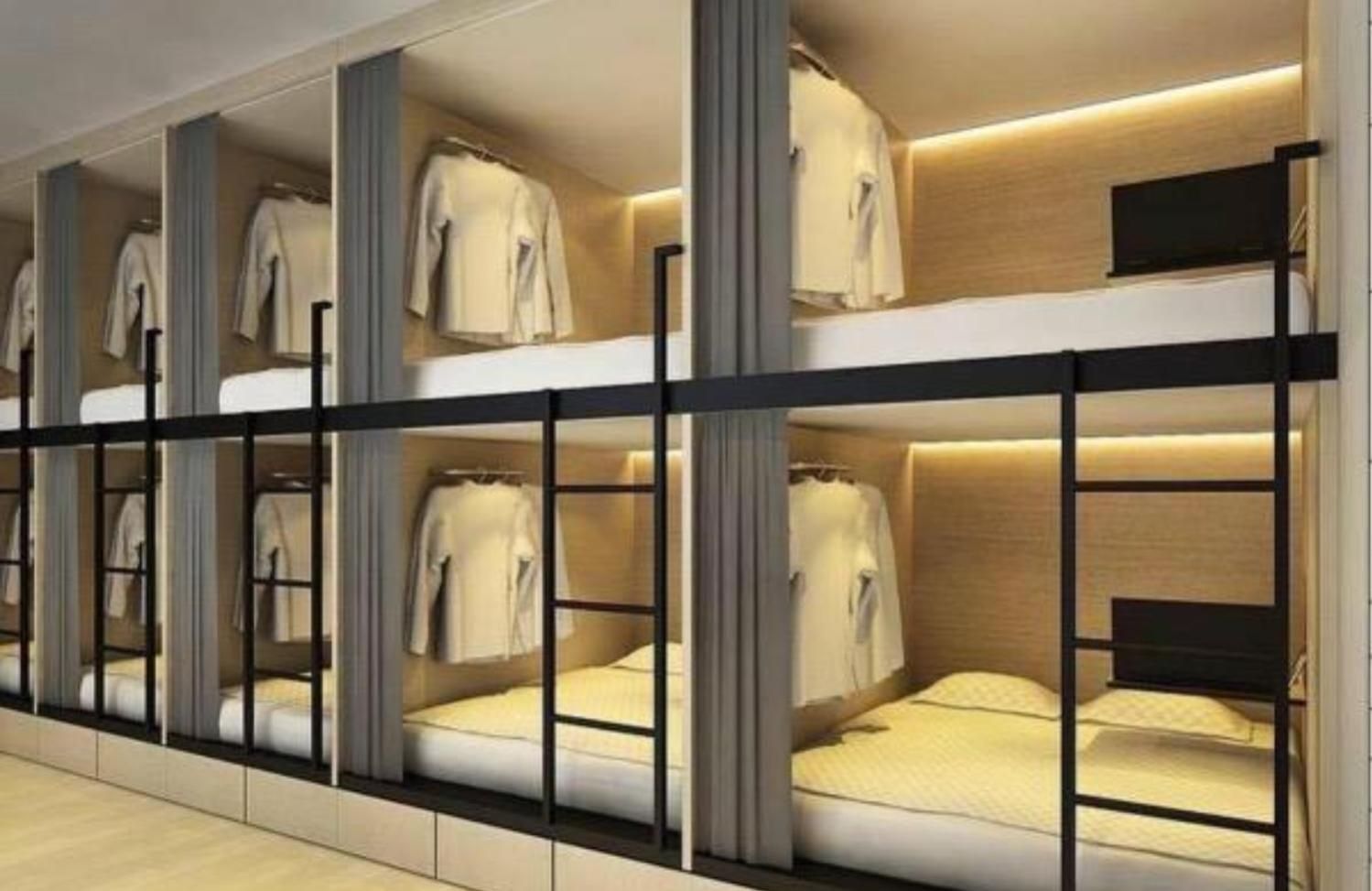 A hotel room with bunk beds, a wardrobe, and a television.