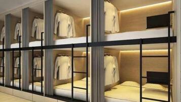 A hotel room with bunk beds, a wardrobe, and a television.