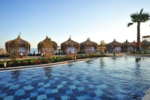 A pool area with thatched umbrellas and a palm tree. - Adenya Hotel & Resort (Alanya)