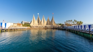 A waterfront hotel with multiple conical tents, a dock with lounge chairs, and a clear blue sky. - Adenya Hotel & Resort (Alanya)