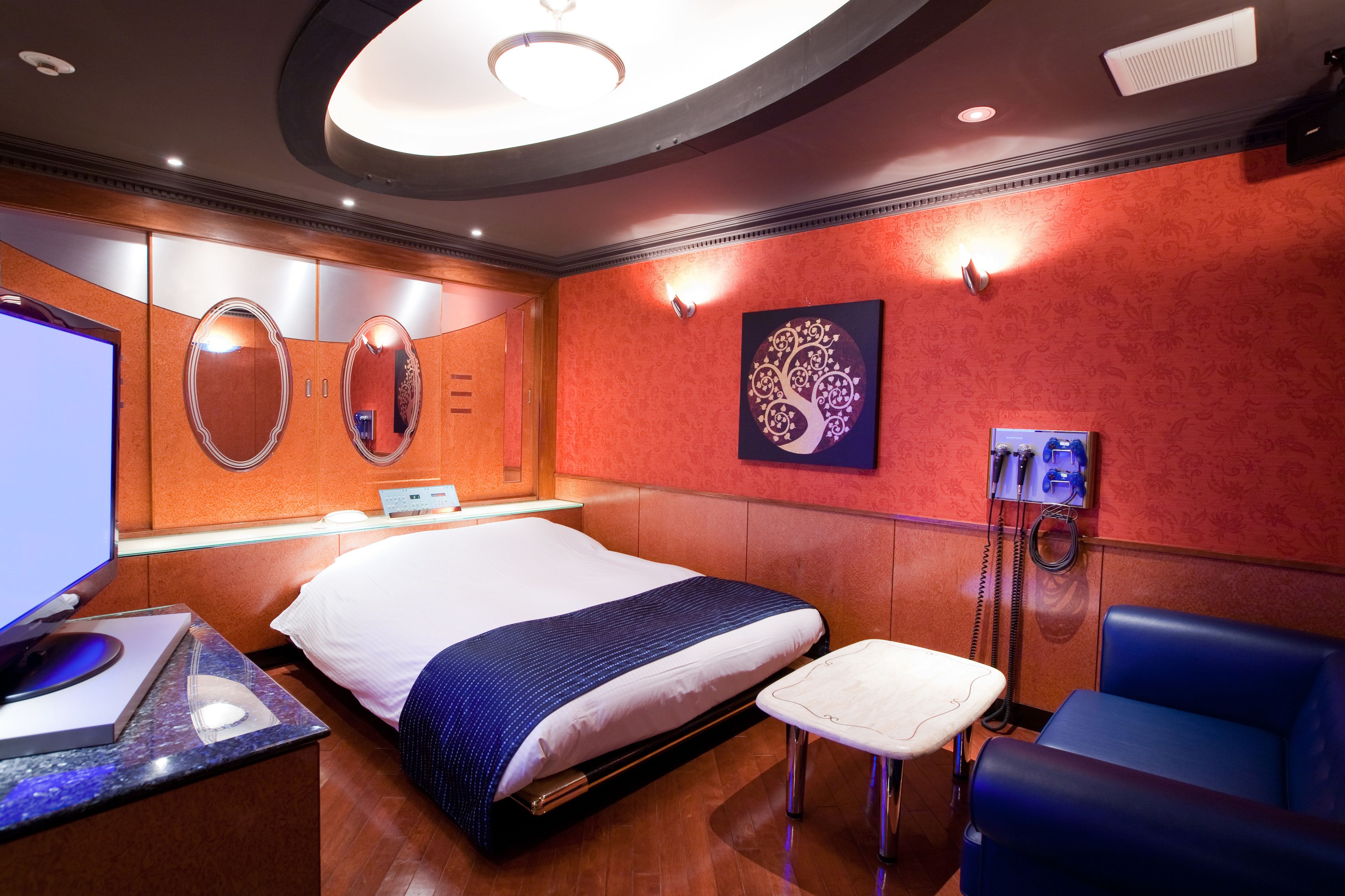 A modern hotel room with a large bed, a desk with a computer, a phone, and a seating area.