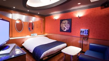 A modern hotel room with a large bed, a desk with a computer, a phone, and a seating area.