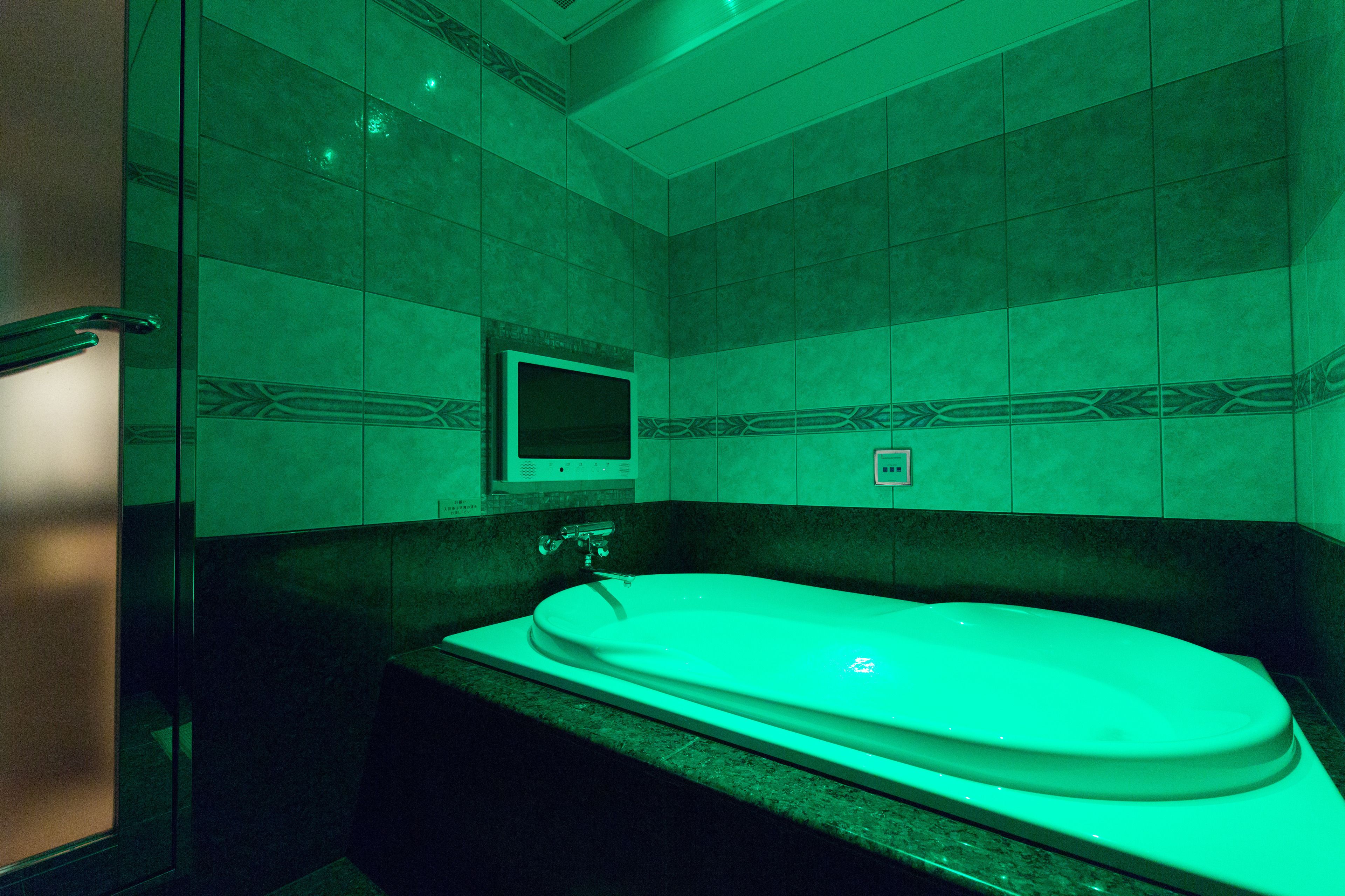 A bathroom with a freestanding bathtub, a mirror above the tub, and patterned tiles on the walls.