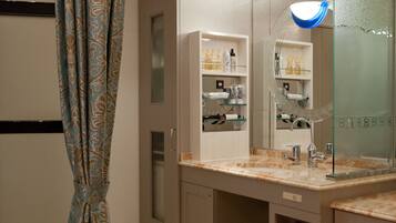 A modern bathroom with a shower curtain, a glass-enclosed vanity, and a marble-tiled floor.
