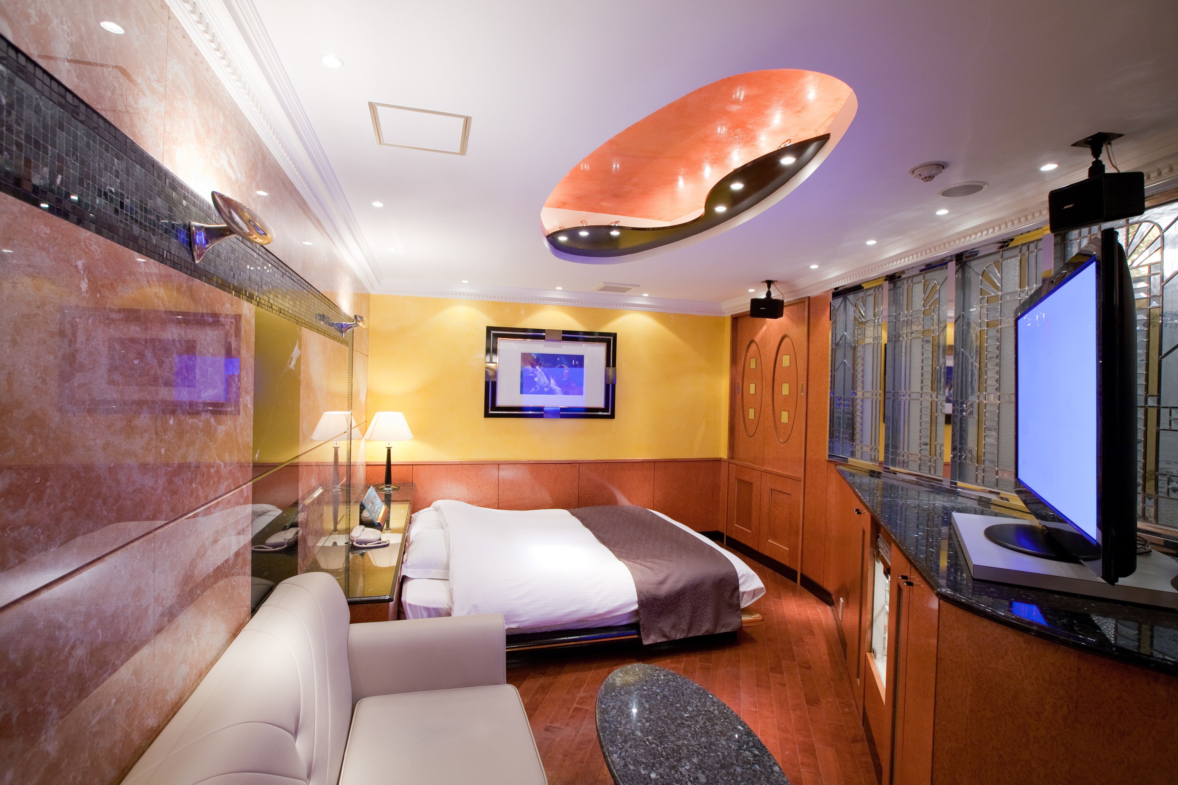Ein modernes Hotelzimmer mit Bett, Sofa, Fernseher und großem Fenster.