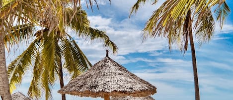 Na praia, espreguiçadeiras, guarda-sóis, toalhas de praia 