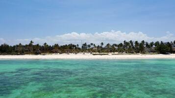 Un complejo turístico en la playa con aguas turquesas cristalinas, arena blanca y palmeras.