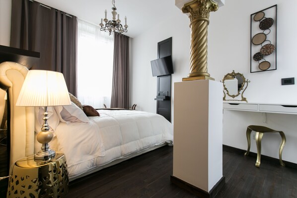 A modern hotel room with a large bed, a desk, a chair, a TV, and a chandelier. - Aparthotel dei Mercanti (Milan)