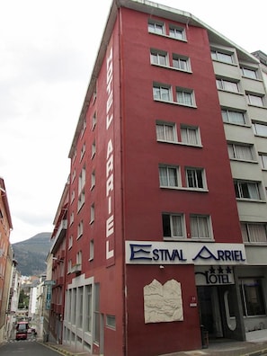 A red hotel building with a sign for 'ESTNAL ARRIEL HOTEL' and a visible entrance.
