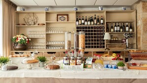 A buffet setup with various food items, a wine rack, and glassware. - Hotel Iris (Pescasseroli)