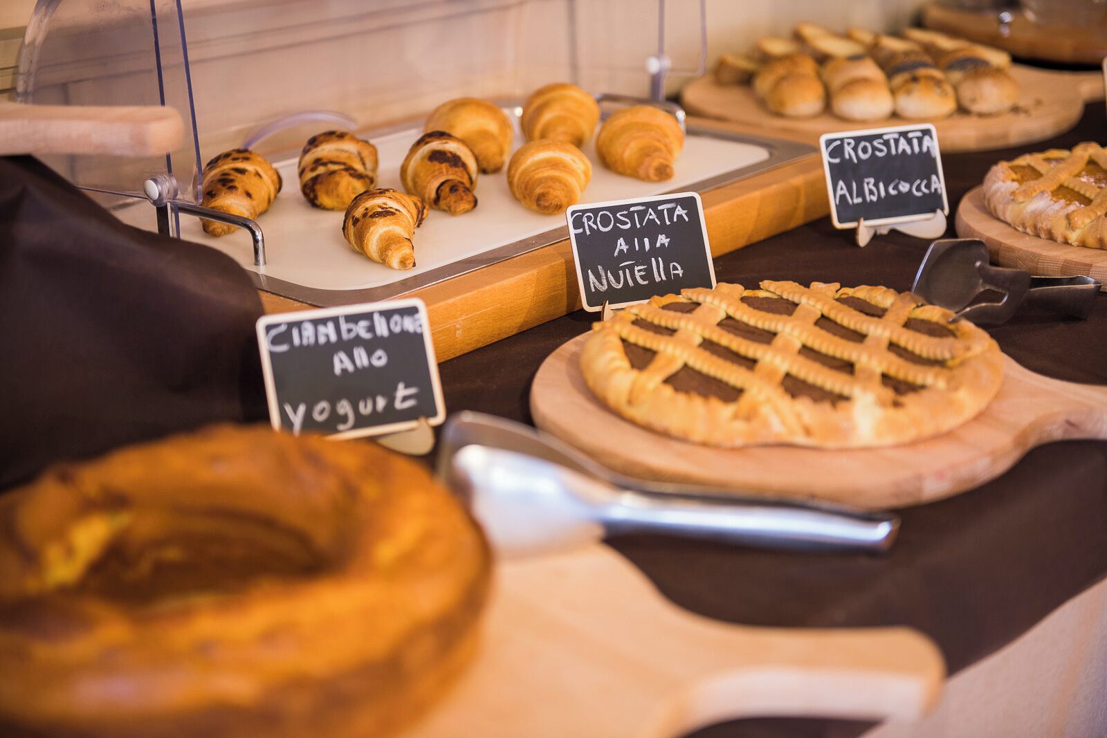 A bakery display with croissants, a pie, and signs indicating available items like crosta alla nutella and ciabatta.