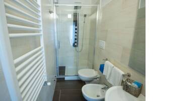 Un baño pequeño con ducha, inodoro y lavamanos.