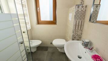 Une salle de bain comprenant des toilettes, un bidet et un lavabo.