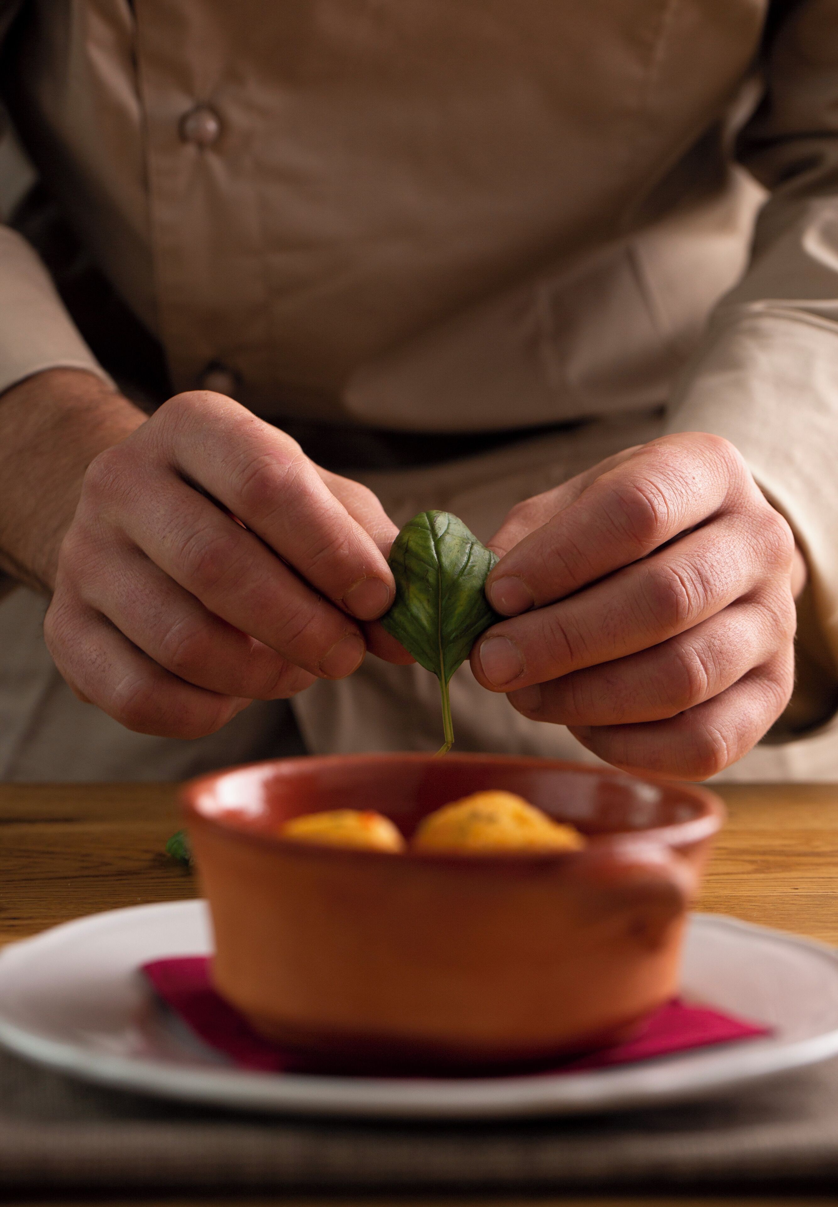 Una persona che tiene una foglia sopra una ciotola di cibo.