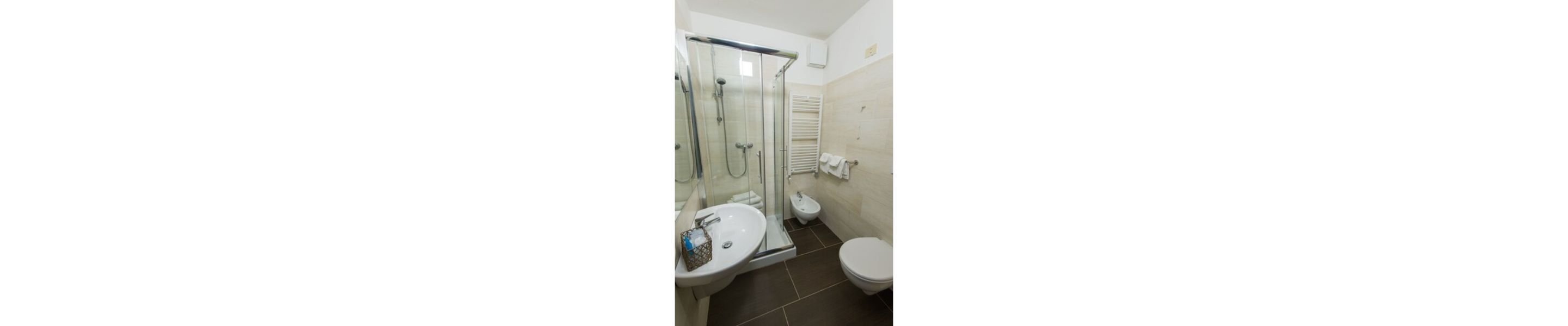 Un bagno con box doccia in vetro, un water e un lavandino.