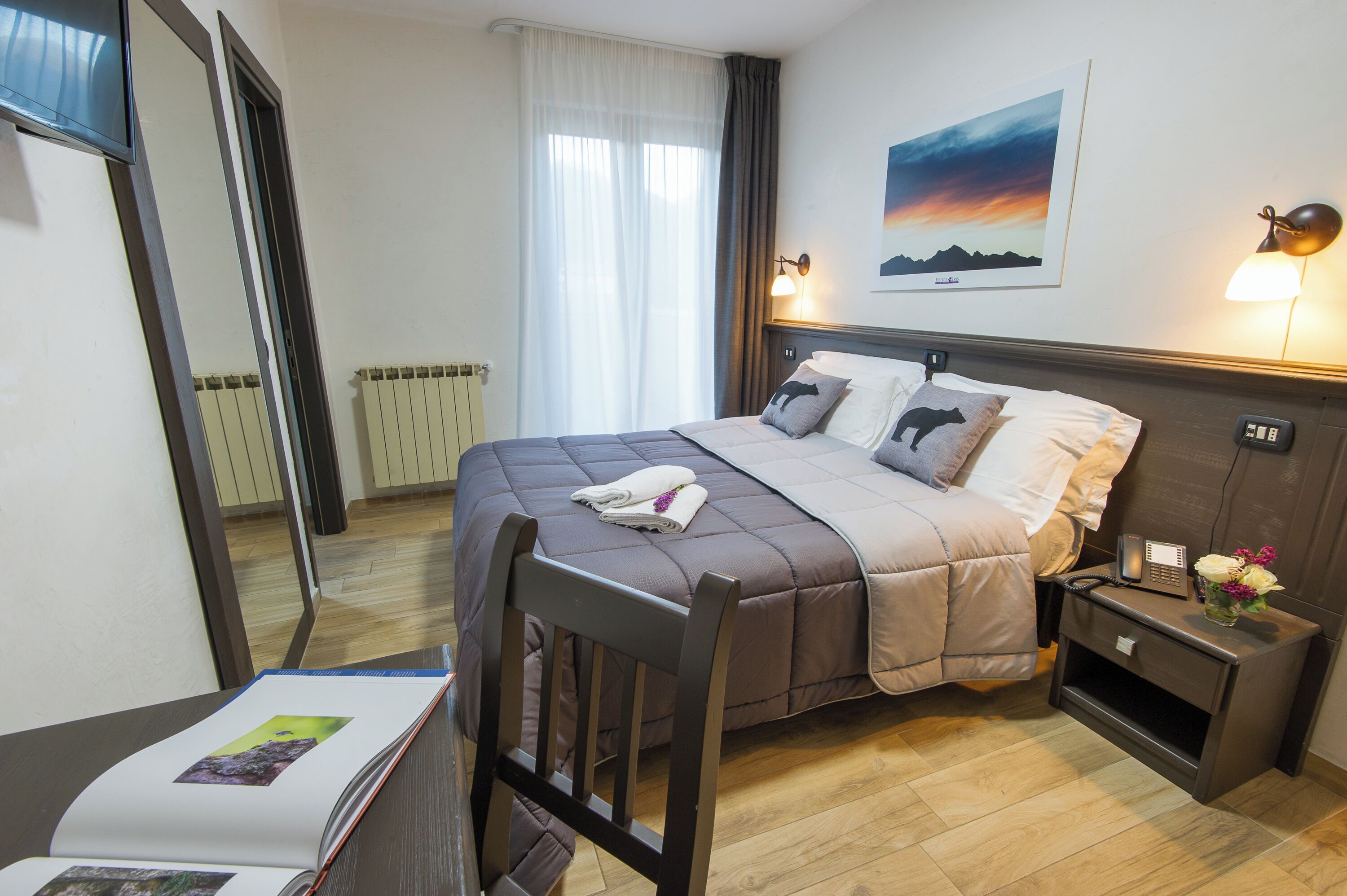 Ein ordentlich eingerichtetes Hotelzimmer mit Bett, Nachttischen, Schreibtisch und Stuhl.