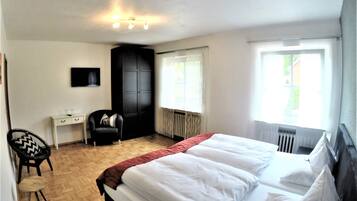 Ein Schlafzimmer mit einem Bett, einem Schreibtisch, einem Stuhl und einem Kleiderschrank.