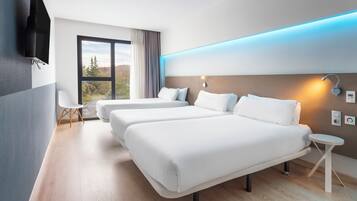 Une chambre d’hôtel moderne avec deux lits, une télévision, une petite table et une vue sur l’extérieur.