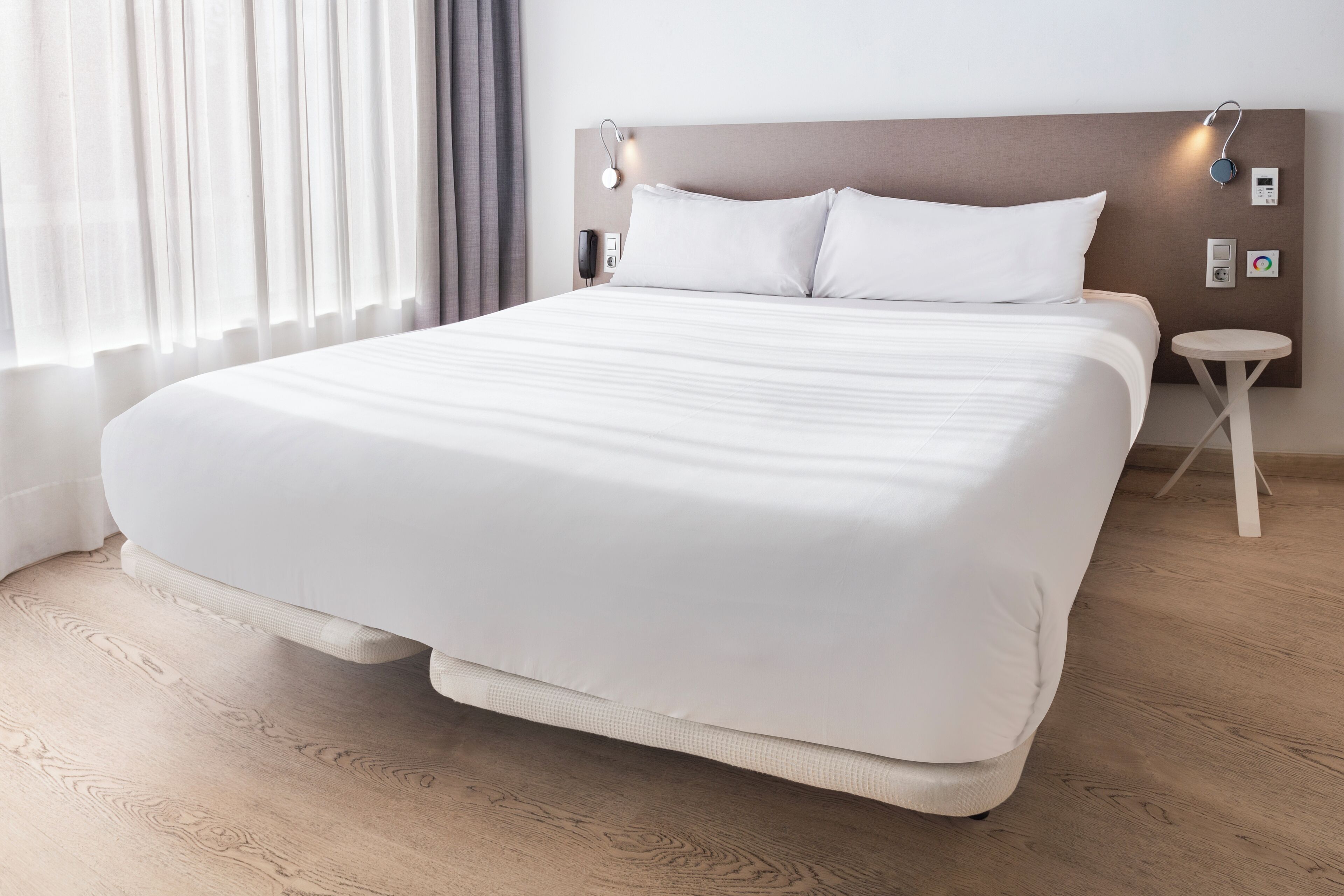 Una cama grande con cabecera de madera, una mesita de noche y una pequeña mesa redonda.