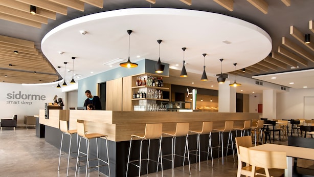Een moderne bar met een gebogen toonbank, barstoelen en hanglampen.