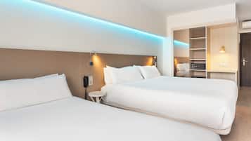 Une chambre d’hôtel avec deux lits, une table de chevet, une armoire intégrée et un petit bureau avec une chaise.