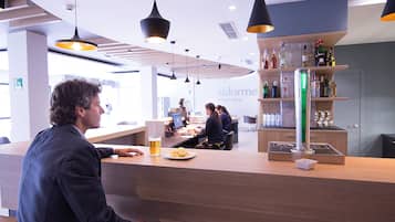 Eine moderne Bar mit Holztresen, Zapfhahn und einer Flaschenregal.
