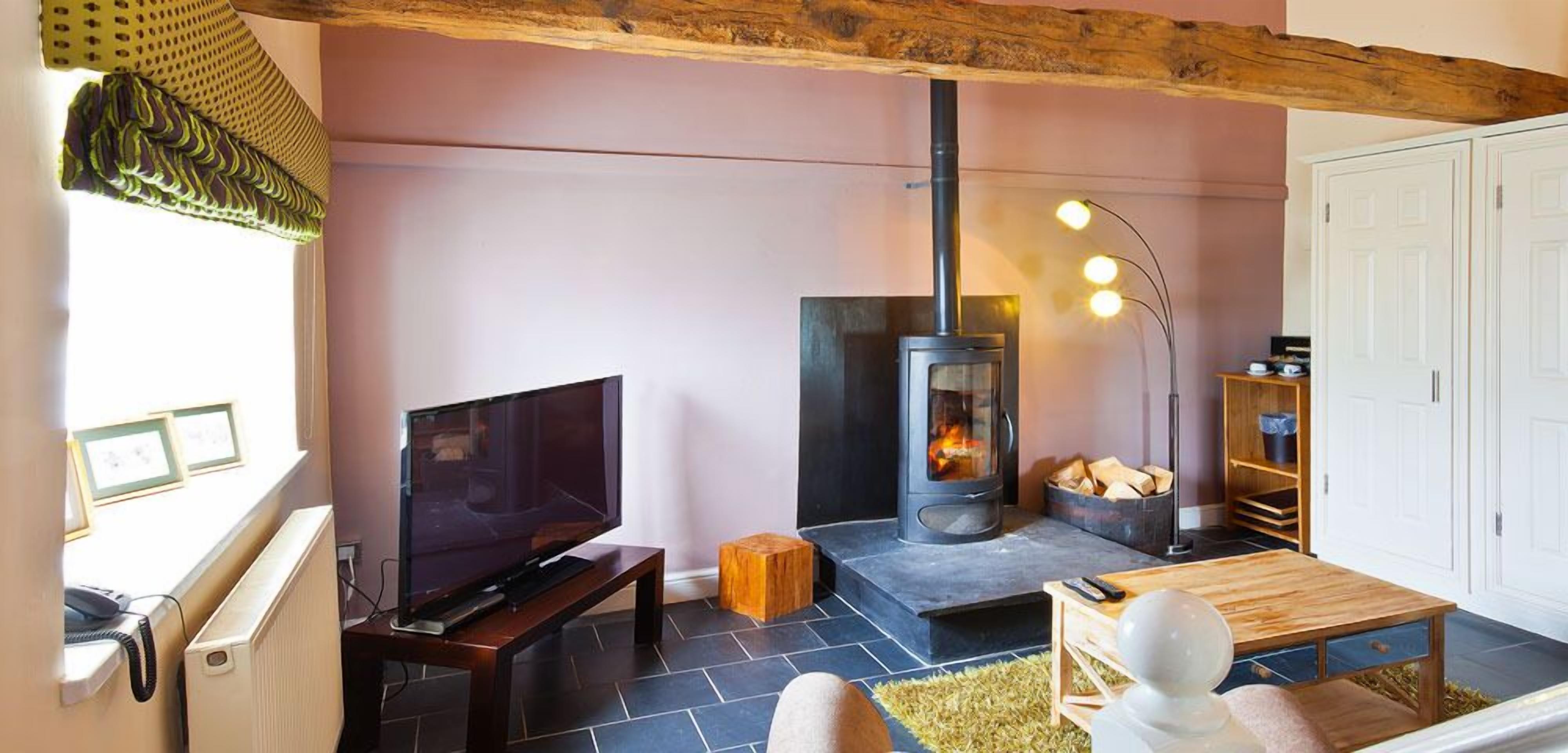 A cozy living room with a fireplace, a television on a stand, and a wooden table.