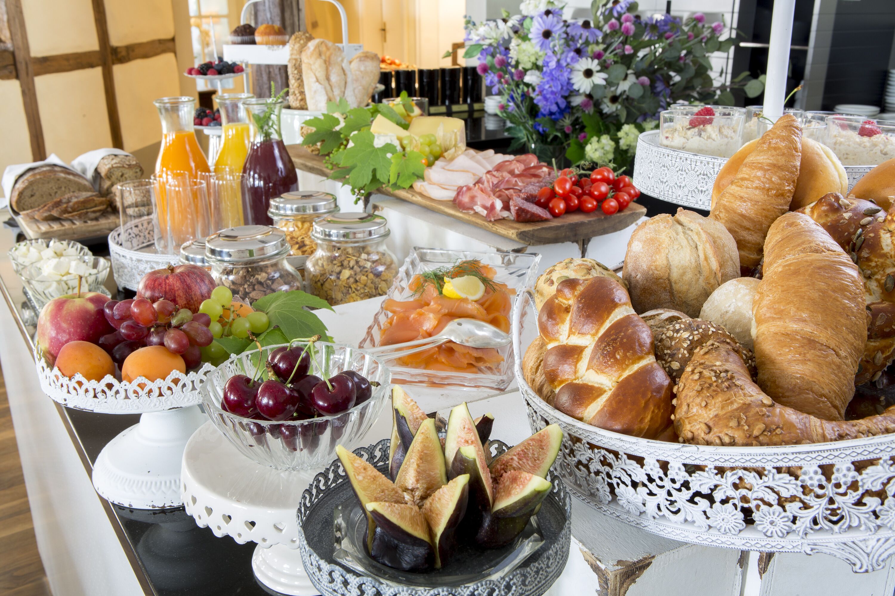 A buffet table with various food items including fruits, cheeses, meats, and breads.